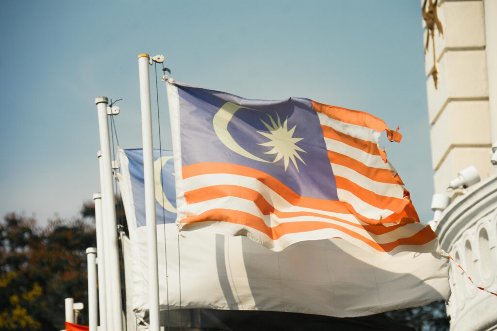 A vibrant Malaysian flag waving against a clear blue sky symbolizes national pride and patriotism.