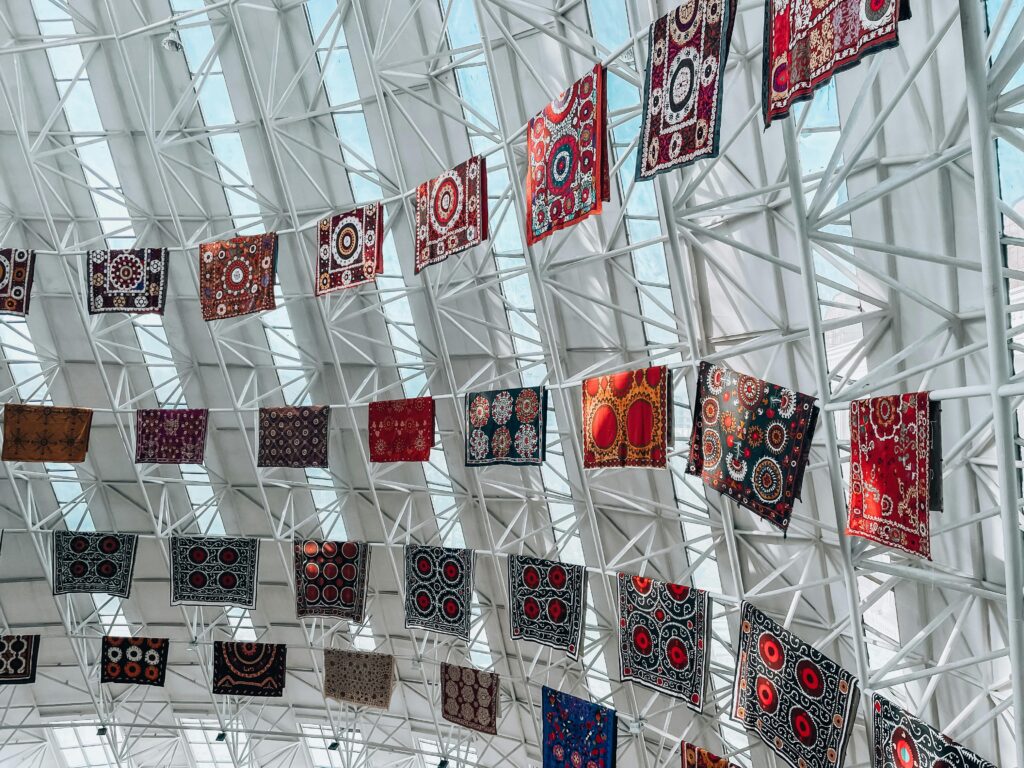 Colorful textiles suspended from a geometric skylight in Dushanbe, creating a vibrant and artistic display.