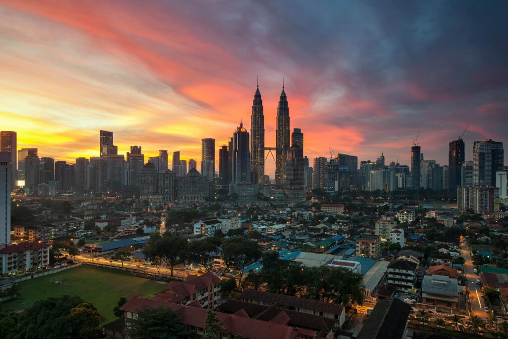 Breathtaking view of Kuala Lumpur skyline with Petronas Towers at sunset, showcasing vibrant urban architecture.