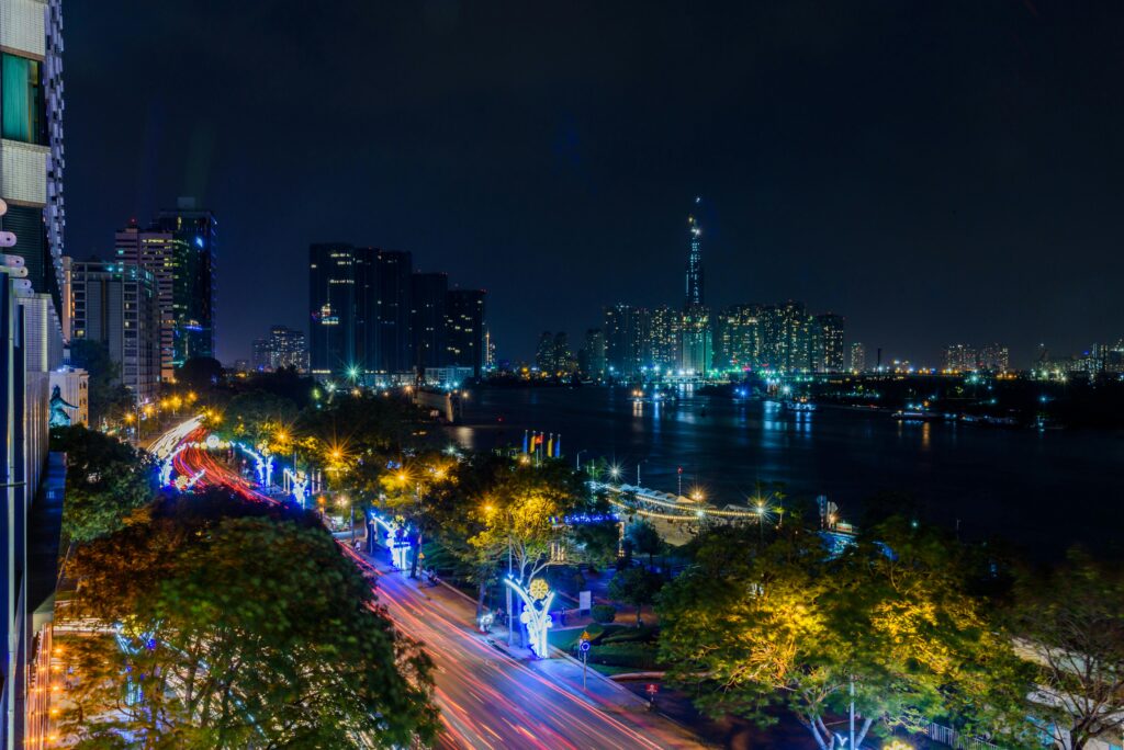 Stunning nighttime view of Ho Chi Minh City's skyline with illuminated roads and skyscrapers by the Saigon River.