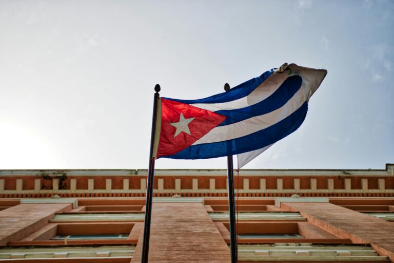 Cuban flag waving against a historic building in Havana, capturing national pride and architectural beauty.