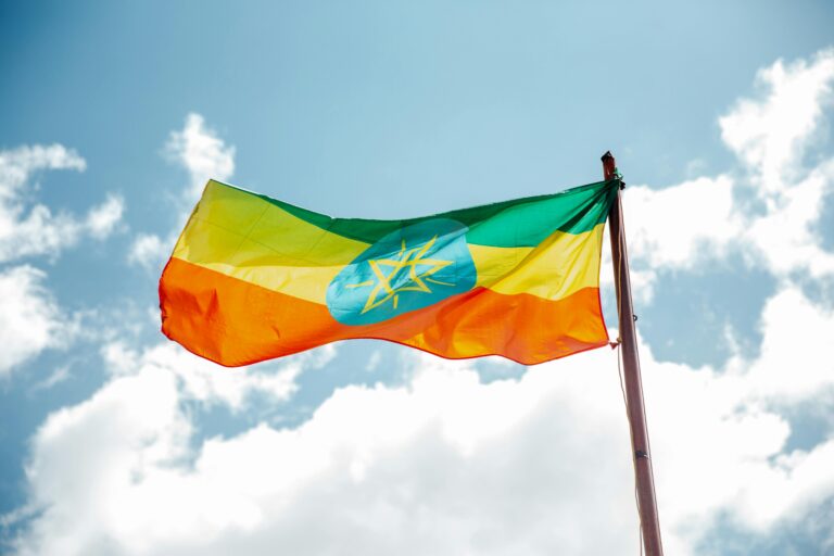 Ethiopian national flag waving under a clear blue sky, symbolizing freedom and hope.